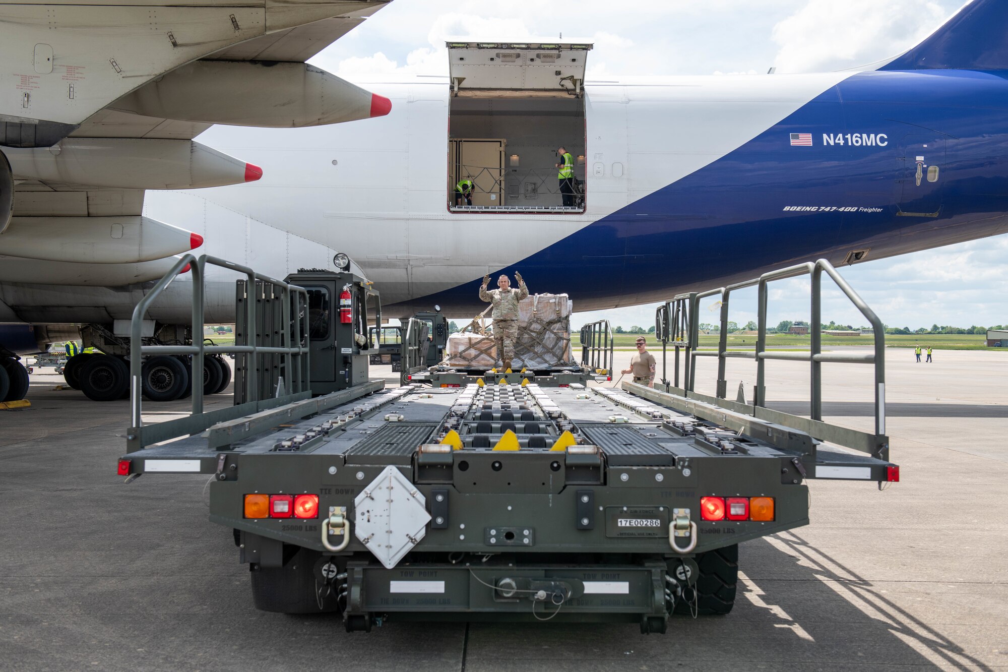 Airman guides a K-loader to offload equipment from an Atlas Air Boeing 767 aircraft