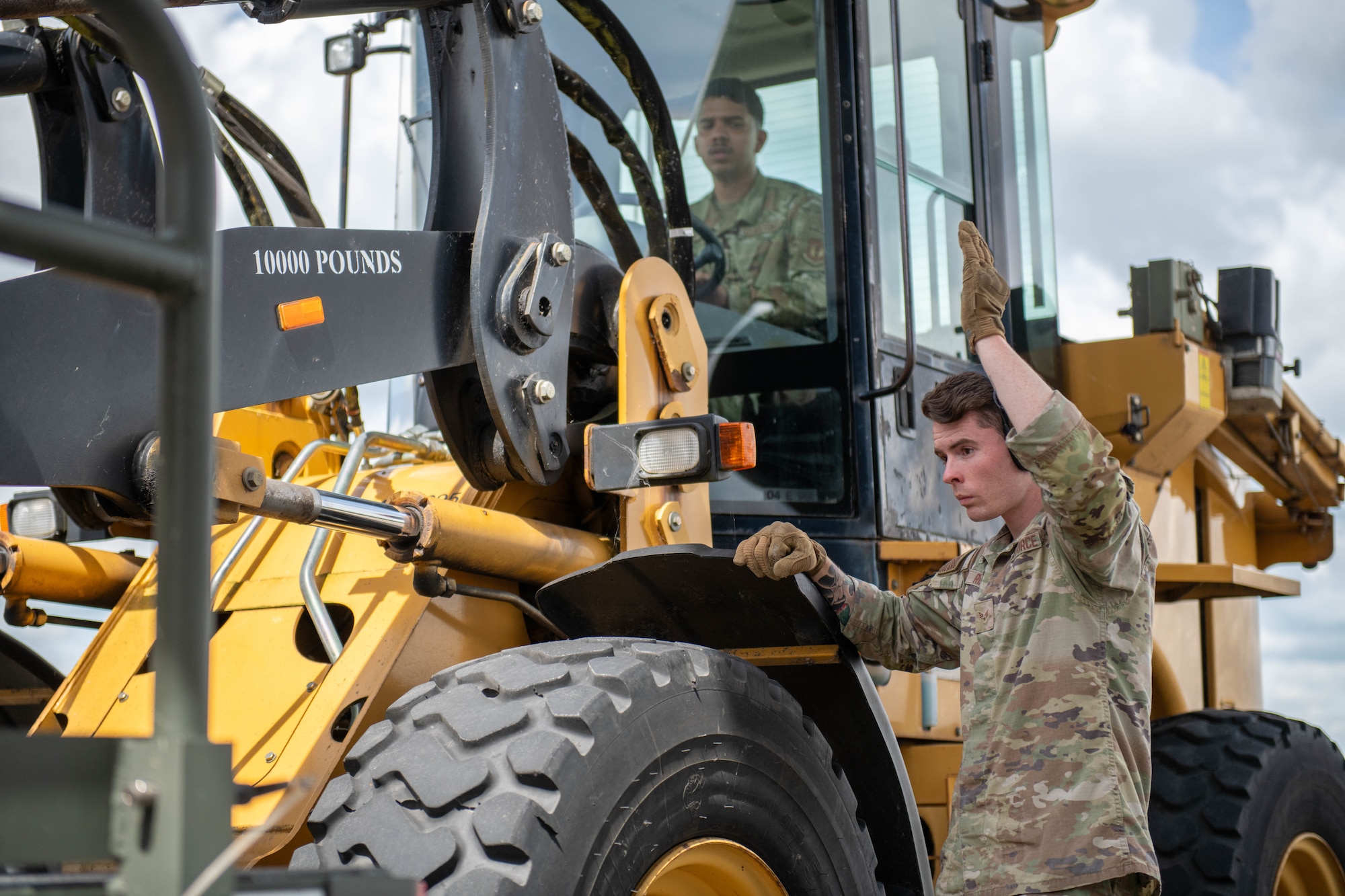 Airmen guide a 10K all terrain forklift operator during an offload