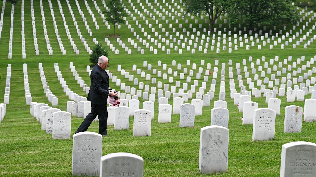 Secretary of the Air Force Frank Kendall places American flags on the graves of fallen service members at Arlington National Cemetery
