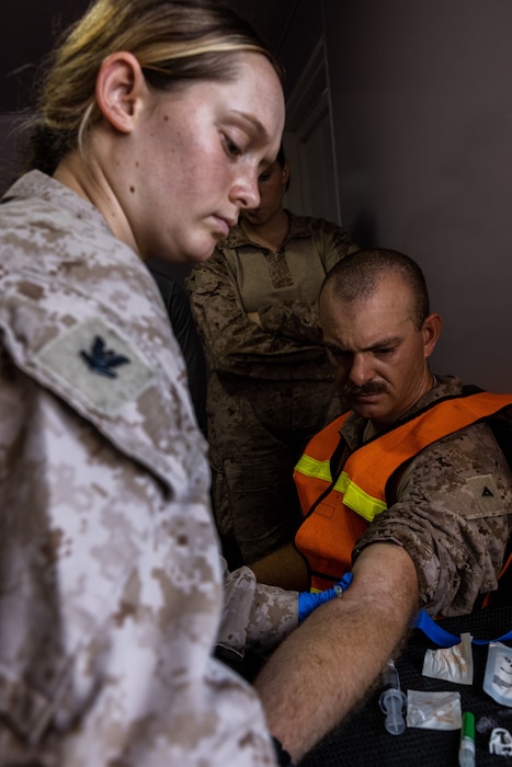 240522-M-JI447-1174 U.S. Navy Hospital Corpsman Third Class Emma Ratzlaff with 2nd Distribution Support Battalion, Combat Logistics Regiment 2, 2nd Marine Logistics Group, performs intravenous therapy during exercise Native Fury 24 at a port in the United Arab Emirates, May 22, 2024. Exercise Native Fury 24 is a key multi-lateral exercise sponsored by U.S. Central Command and executed by U.S. Marine Corps Forces Central Command in collaboration with the Kingdom of Saudi Arabia and the United Arab Emirates. This iteration emphasizes the strategic use of logistics and leverage the extensive network of roads and infrastructure across the Arabian Peninsula. (U.S. Marine Corps photo by Cpl. Meshaq Hylton)