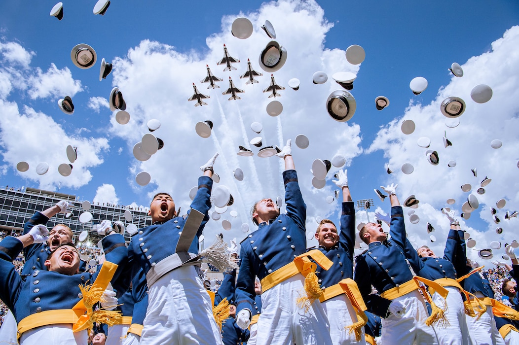 The U.S. Air Force Academy Class of 2024 graduates toss their hats skyward as the U.S. Air Force Air Demonstration Squadron “Thunderbirds” roar overhead