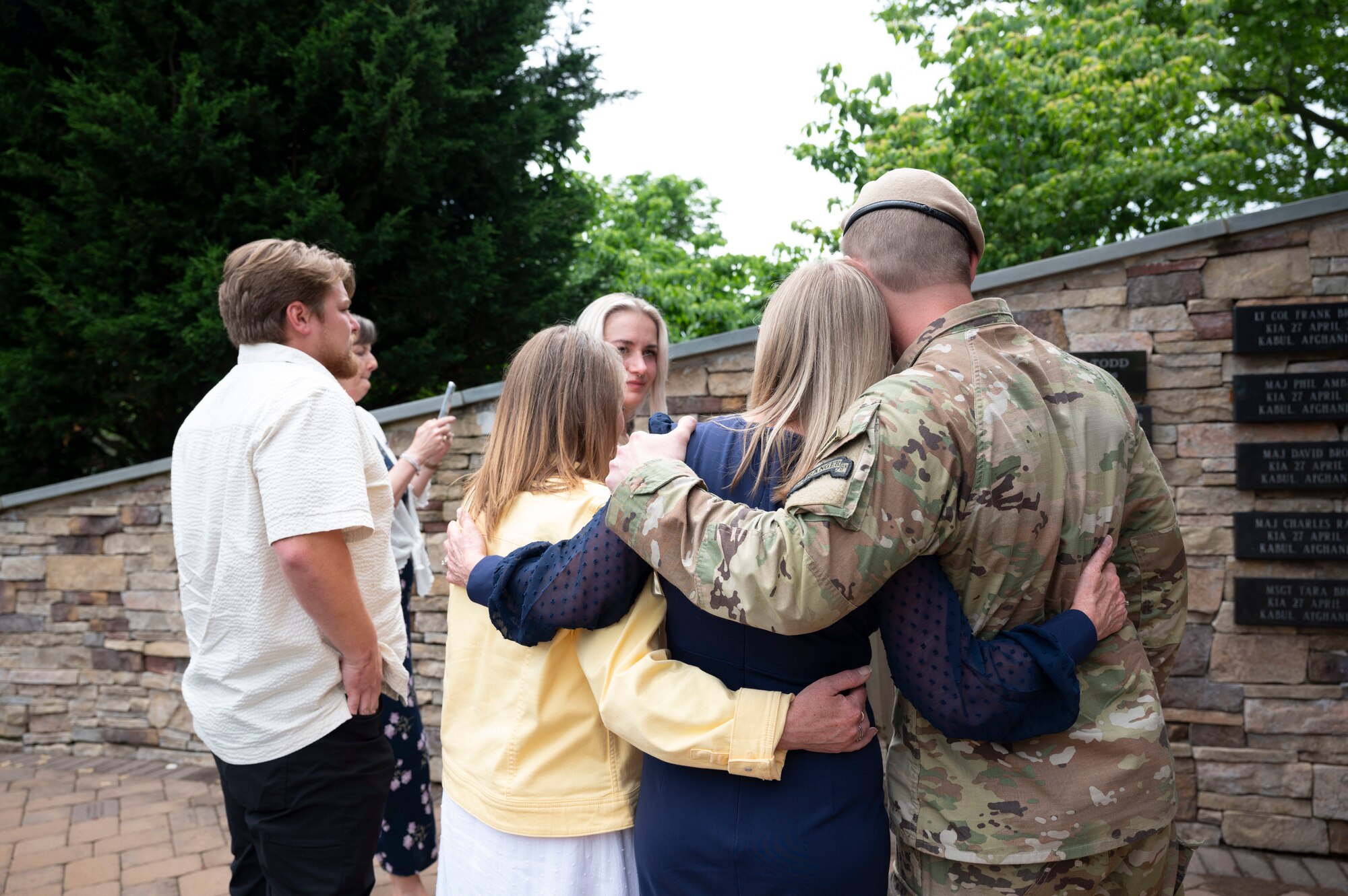 The family of U.S. Air Force Maj. William Downs embrace in front of a plaque bearing his name May 23, 2024, at Joint Base McGuire-Dix-Lakehurst, N.J.