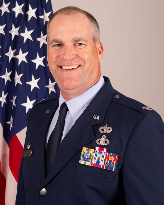 A photo of Col. David Borden, 434th Mission Support Group commander, in his dress blues in front of an American flag. He is smiling.