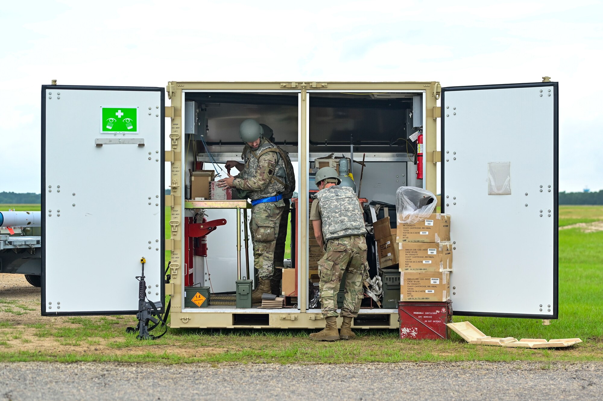 Two airmen working inside a storage container.