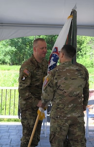 Army Colonel in Soldier uniform hands a United States Army Recruiting Battalion guidon to an Army Lieutenant Colonel during a change of command ceremony.