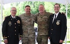 Photograph showing two Army Soldiers, posed with smiles in the center, surrounded by a smiling Army Chaplain on either side