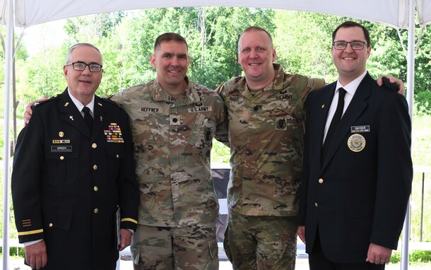 Photograph showing two Army Soldiers, posed with smiles in the center, surrounded by a smiling Army Chaplain on either side