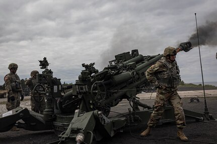 U.S. Army Sgt. 1st Class Jon Soucy, a photojournalist for the National Guard Bureau, pulls the trigger cord on an M777 howitzer May 11, 2024, as part of DEFENDER 24 in Ustka, Poland. Members of B Battery, 2nd Battalion, 123rd Field Artillery Regiment, Illinois Army National Guard invited Soucy as a guest firer to join their field artillery fire mission. DEFENDER 24 includes live-fire exercises, wet gap crossings, and other training to strengthen interoperability among participants. (U.S. Army photo by Sgt. 1st Class Chad Menegay)