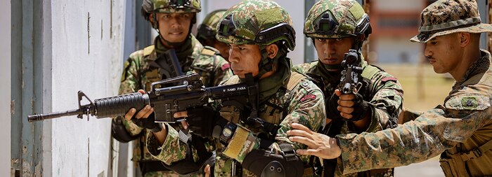 240530-M-WH287-1353 SRI PANTAI CAMP, Malaysia (May 30, 2024) U.S. Marine Corps Sgt. Christopher Rios, a squad leader assigned to Charlie Company, Battalion Landing Team 1/5, 15th Marine Expeditionary Unit, directs Malaysian soldiers assigned to 9th Battalion, Royal Malay Regiment, 10th Brigade (Para), to designated positions during an urban operations subject matter expert exchange during Tiger Strike 24 at Sri Pantai Camp, Kuala Terengganu, Malaysia, May 30, 2024. Tiger Strike is a bilateral exercise between U.S. and Malaysia armed forces designed to enhance communication and build combat readiness through combined amphibious operations and subject matter expert exchanges in support of a shared vision for security and stability in the region. (U.S. Marine Corp photo by Gunnery Sgt. Antonio Campbell)