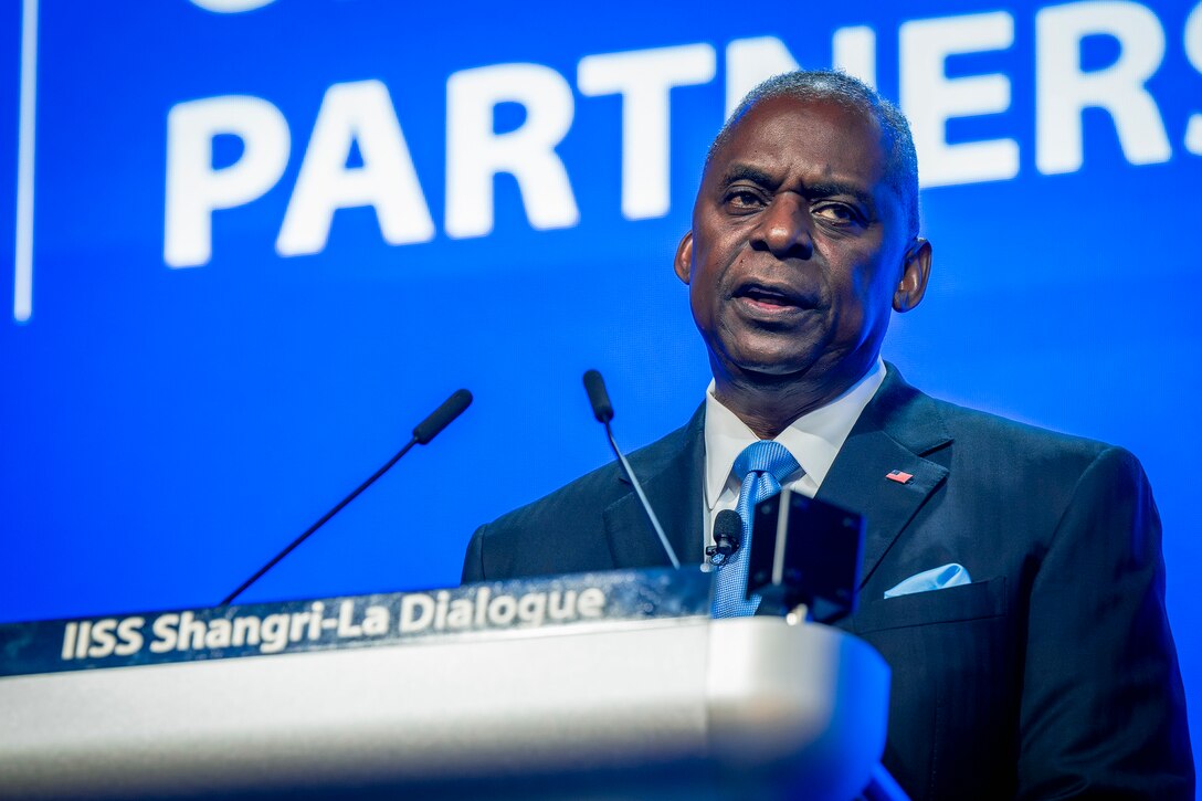 A person in a business suit speaks at a podium.