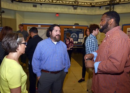 JOINT BASE SAN ANTONIO-FORT SAM HOUSTON – (May 30, 2024) – Dr. Luis Martinez (center), of San Angelo, Texas, a research microbiologist, joined by Tarea Burton, a research associate, assigned to the Biomaterials Department, Craniofacial Health and Restorative Medicine Directorate, Naval Medical Research Unit (NAMRU) San Antonio, speaks with an attendee of the inaugural Promote Professional Engagement amongst Military Laboratories (ProPEL) Science Symposium held at the Center of the Intrepid. The event was designed for researchers within Joint Base San Antonio to better understand the type of work they are conducting to further collaborative opportunities. NAMRU San Antonio is one of the leading research and development laboratories for the U.S. Navy under the Department of Defense (DoD) and is one of eight subordinate research commands in the global network of laboratories operating under the Naval Medical Research Command in Silver Spring, Md.  Its mission is to conduct gap driven combat casualty care, craniofacial, and directed energy research to improve survival, operational readiness, and safety of DoD personnel engaged in routine and expeditionary operations. (U.S. Navy Photo by Burrell Parmer, NAMRU San Antonio Public Affairs/Released)