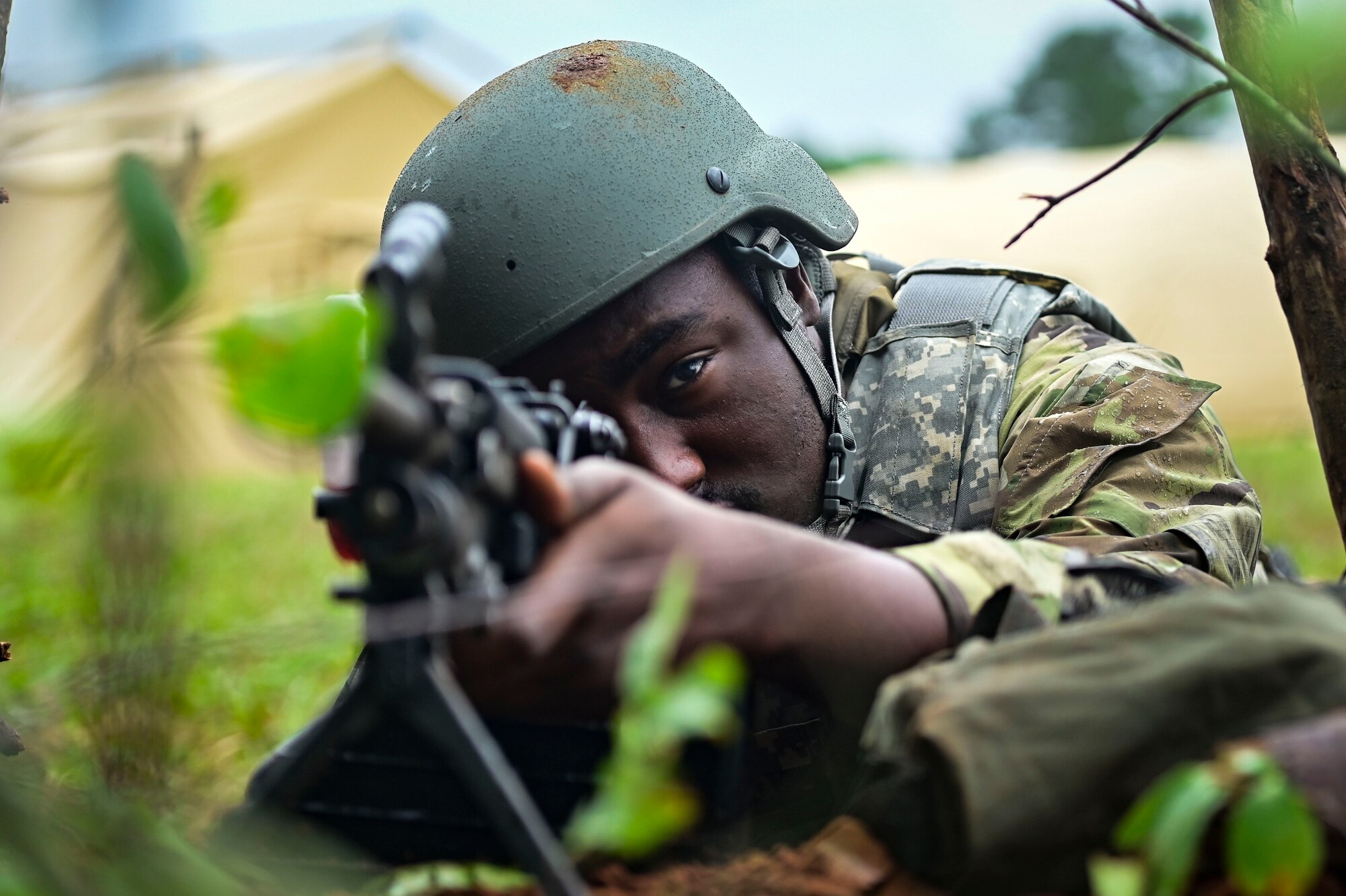 Airmen aiming with a rifle in the woods.