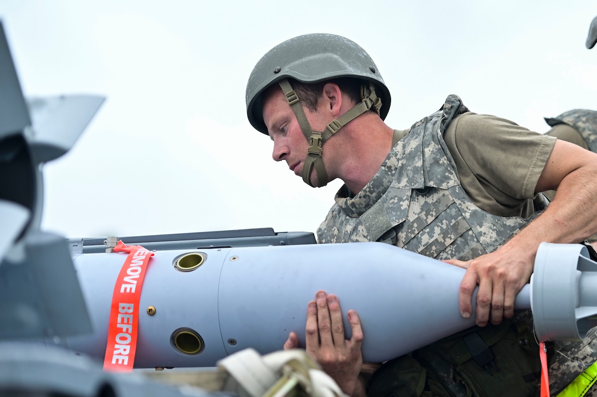 Airmen working on a bomb outside.