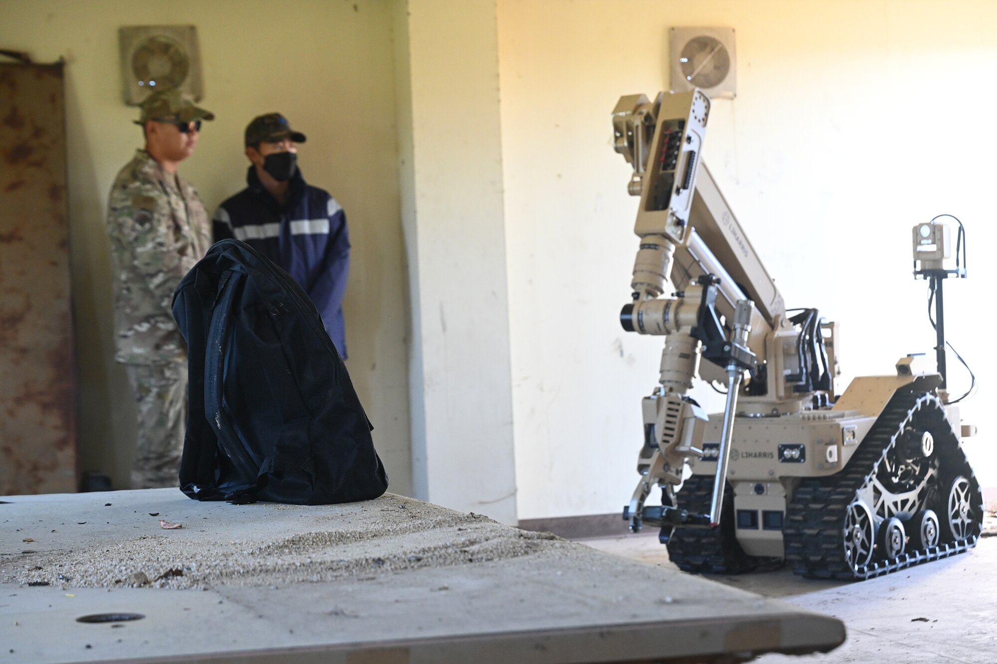 Senior Airman Steven Nguyen, left, 8th Civil Engineer Squadron explosive ordnance disposal technician, stands alongside Senior Airman Yi Sung-Won, Republic of Korea Air Force 38th Fighter Wing translator, while a T7 EOD robot performs initial reconnaissance during joint EOD training at Kunsan Air Base, ROK.