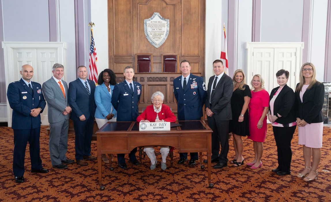 Air Force Culture and Language Center personnel, Air War College Commander Col. Kevin “Buddy” Lee, and AWC Senior Enlisted Leader Chief Master Sgt. Richard Brownlee Jr., watch as Alabama Governor Kay Ivey signs a proclamation on Oct. 10, 2024, declaring November as Alabama’s Second Annual Language, Regional Expertise, and Culture Month in honor of the 9th Annual Air University LREC Symposium at Maxwell Air Force Base, Ala. L-R: Capt. Alexandru Stoica, James Brown, Chad Hermann, Robin Hunter, Col. Kevin “Buddy” Lee, Gov. Ivey, Chief Master Sgt. Richard Brownlee Jr., Howard Ward, Jamie Williams, Dr. Susan Steen, Lori Quiller, and Neka Ponn.