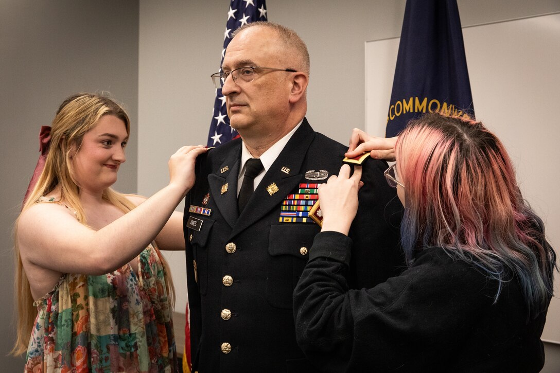 Col. Kevin Jones is promoted by his daughters, Samantha and Sandra.