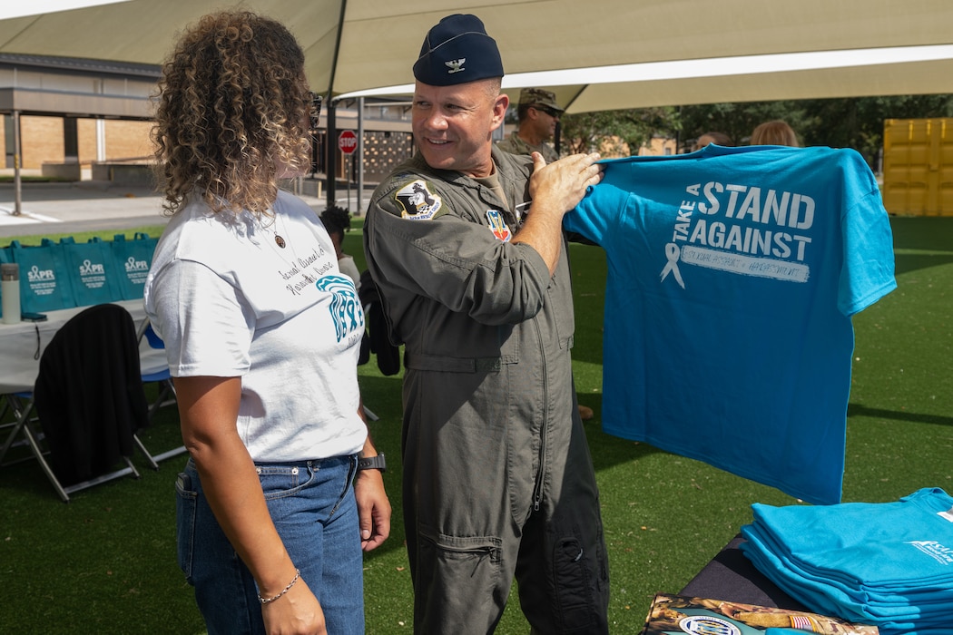 Luzmeilyn Camper, 23rd Wing sexual assault response coordinator, shares Sexual Assault Prevention and Response products with U.S. Air Force Col. Gary Symon, 347th Rescue Group commander, at Moody Air Force Base, Georgia, Sept. 19, 2024. The SAPR office handed out shirts to everyone who attended the event. (U.S. Air Force photo by Airman 1st Class Savannah Carpenter)