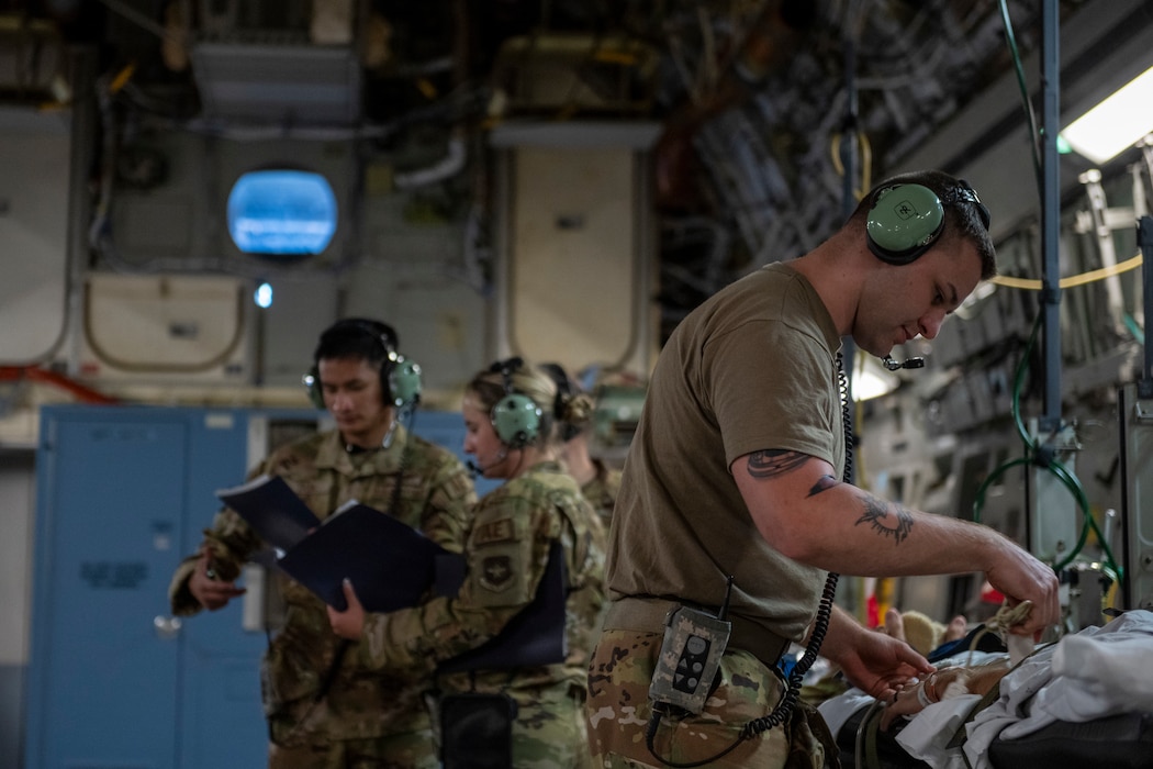 Airmen take vitals on a patient in a C-17