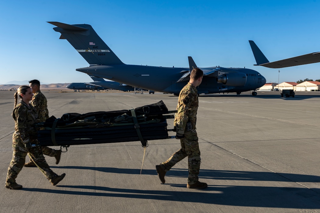 Airmen load medical litter on a C-17 parked on the flight line