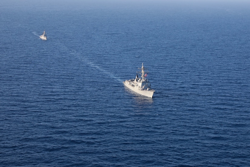 Two military ships sail together at sea.