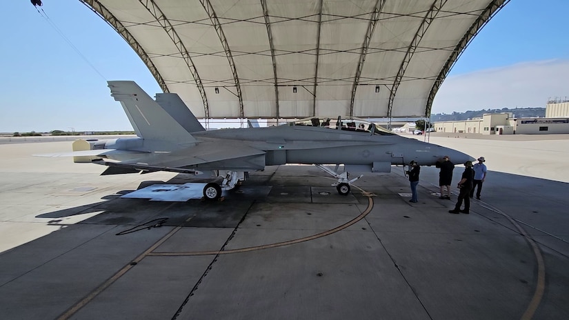 A jet sits in an open air hangar.