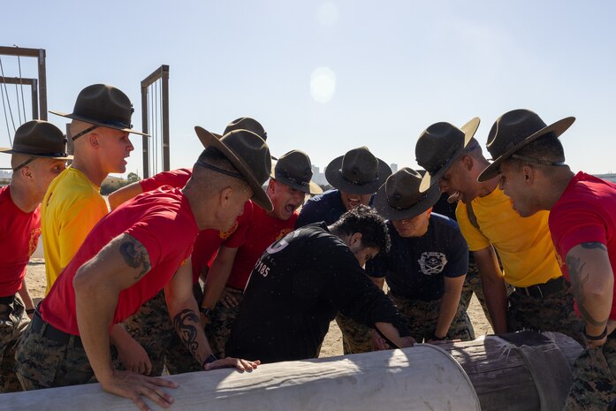U.S. Marine Corps drill instructors, Recruit Training Regiment, Marine Corps Recruit Depot San Diego, encourage a contestant during the Contestants pose for a photo after the 2024 MCRD San Diego Boot Camp Challenge, Oct. 19, 2024. For the past 23 years, MCRD San Diego has hosted the bootcamp Challenge, a three-mile obstacle course race guided by 60 drill instructors that highlights the physical and mental demands of bootcamp. The event fosters camaraderie and community engagement through interaction with MCRD personnel. (U.S. Marine Corps photo by Lance Cpl. Jacob Hutchinson)