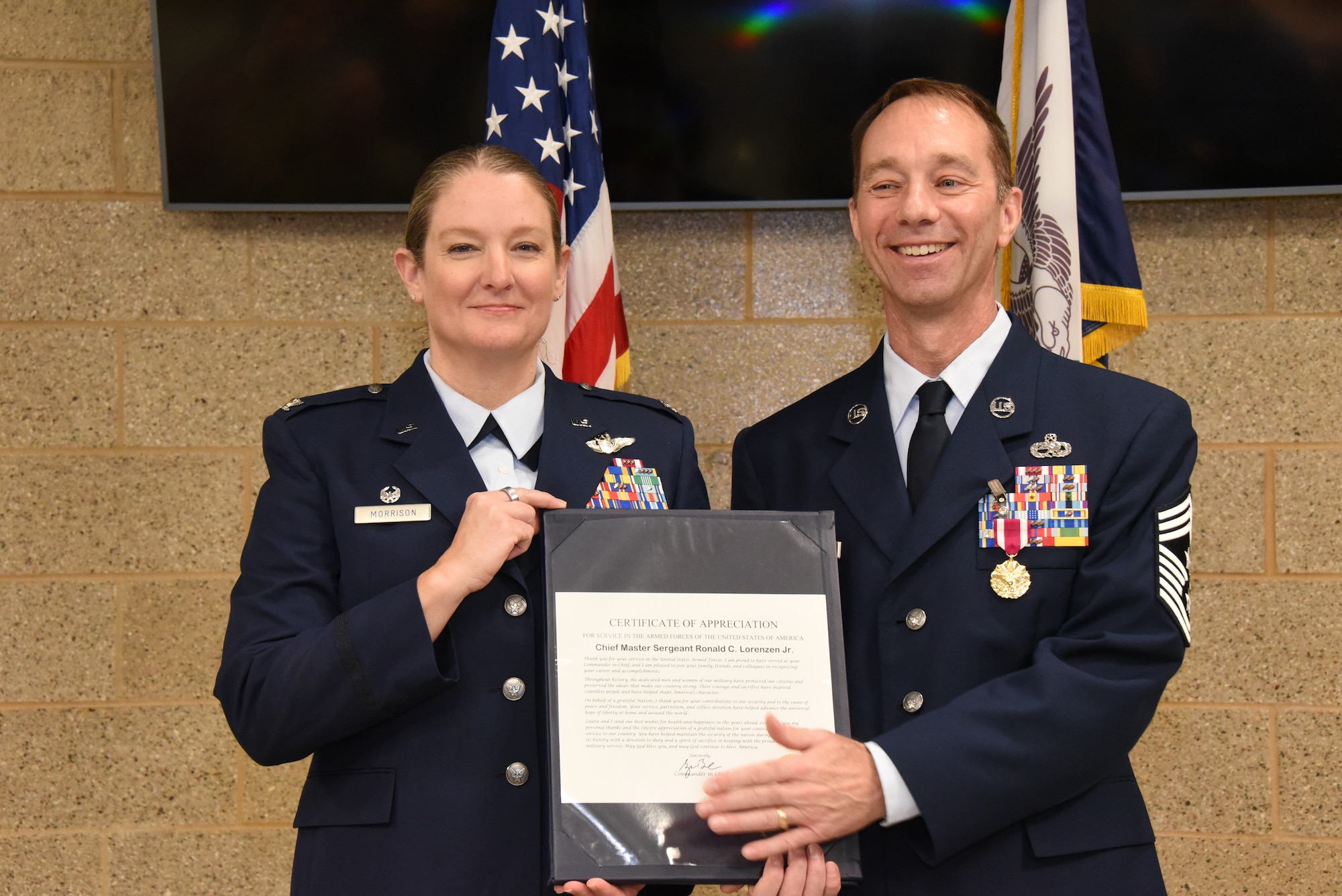 U.S. Air National Guard Command Chief Master Sgt. Ron Lorenzen, right, is presented with presidential letter of appreciation from Col. Sonya Morrison, 185th Air Refueling Wing Commander, left,