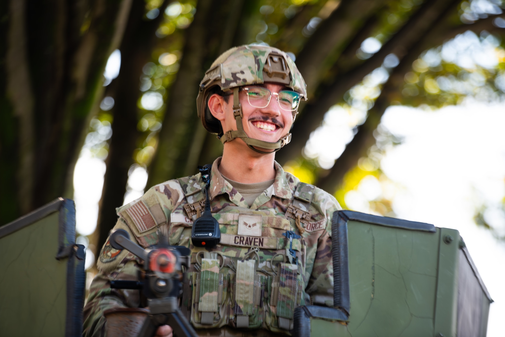 An Airmen on sitting atop of the armored vehicle smiles.
