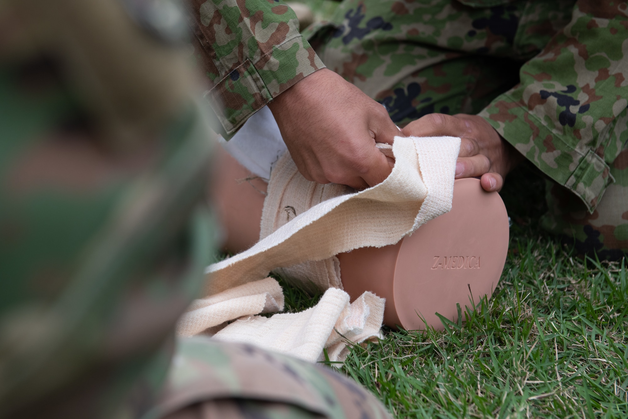 A Japan Ground Self Defense Force member applies a bandage on a simulated patient.