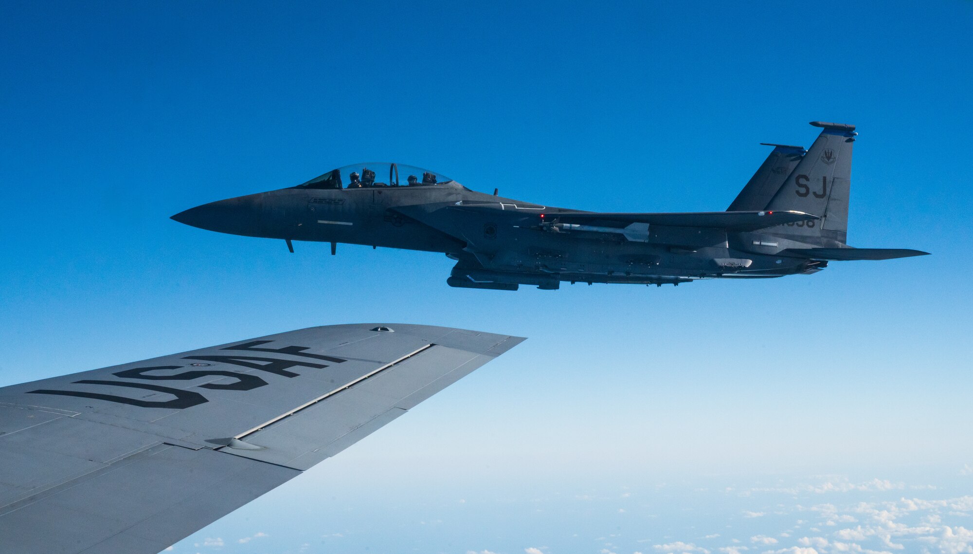 A military jet flies in the clouds, in formation with the military plane from which the photo was taken.