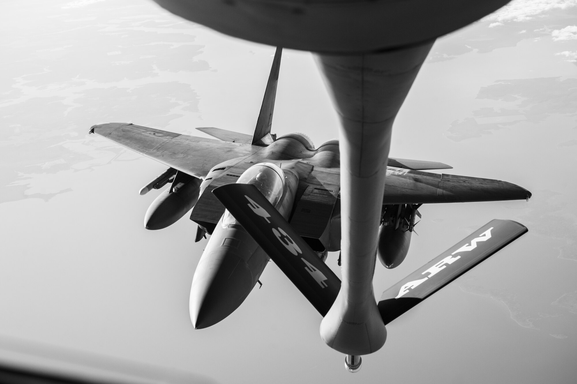 A black and white image of a military aircraft while flying. In the foreground, the boom arm of another military aircraft that reads "434 ARW".