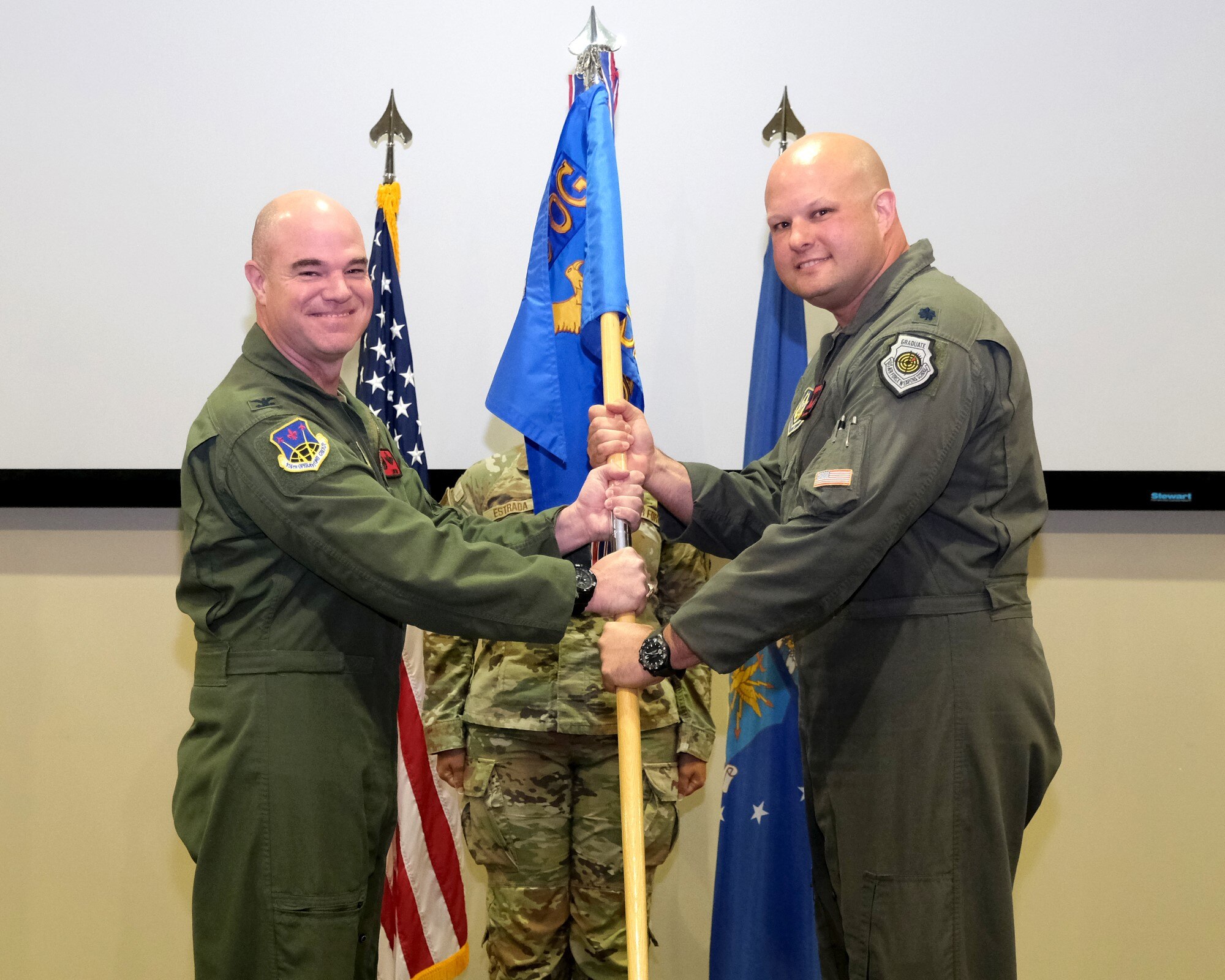 Photo of two uniformed U.S. Air Force military members holding a unit guidon (flag)