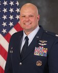 photo of U.S. Air Force Reserve military member in uniform standing in front of a U.S. flag.