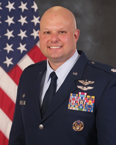 photo of U.S. Air Force Reserve military member in uniform standing in front of a U.S. flag.