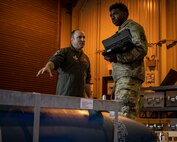 U.S. Air Force Col. Matthew Kenkel, left, 35th Fighter Wing deputy commander, and Senior Airman Devin Britton, 35th Maintenance Squadron Munitions Flight conventional maintenance crew chief, examine an inert MK-84 bomb.