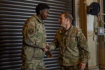 U.S. Air Force Col. Paul Davidson, right, 35th Fighter Wing commander, and Senior Airman Devin Britton, 35th Maintenance Squadron Munitions Flight conventional maintenance crew chief, shake hands.