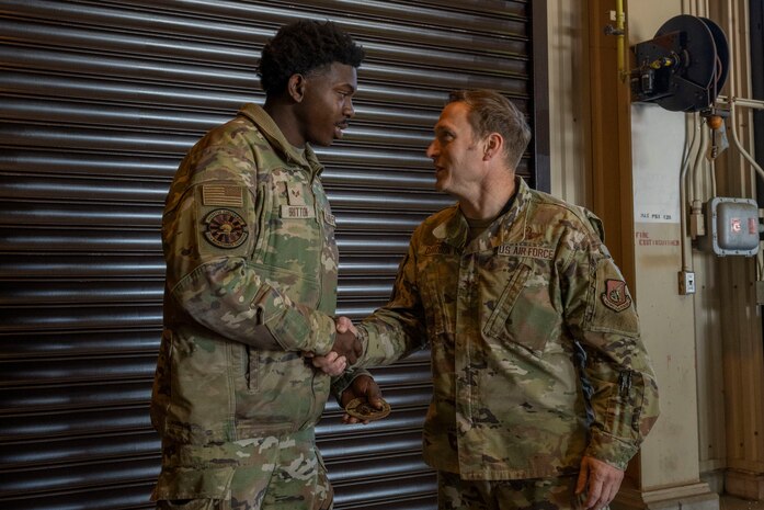 U.S. Air Force Col. Paul Davidson, right, 35th Fighter Wing commander, and Senior Airman Devin Britton, 35th Maintenance Squadron Munitions Flight conventional maintenance crew chief, shake hands.