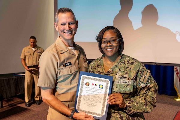 241010-JC800-1010 BETHESDA, Md. (Oct. 10, 2024) - Capt. William Deniston, lead inspector for the Medical Inspector General, awards a certificate of recognition to Chief Hospital Corpsman Kenyetta DeJohn, program director for Diversity, Equity and Inclusion,  during an outbrief for MEDIG. (U.S. Navy Photo by Mass Communication Specialist 1st Class Heath Zeigler)