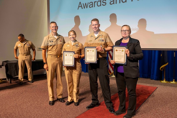 241010-JC800-1016 BETHESDA, Md. (Oct. 10, 2024) - Capt. William Deniston, lead inspector for the Medical Inspector General, awards a certificate of recognition to Lt. Jessica Wentlent, Hospital Corpsman 1st Class Brandon Rowlett and Ms. Dana Hiatt, program managers for the performance evaluation system and awards and recognition progam,  during an outbrief for MEDIG. (U.S. Navy Photo by Mass Communication Specialist 1st Class Heath Zeigler)