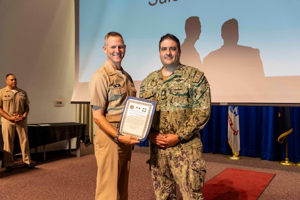 241010-JC800-1018 BETHESDA, Md. (Oct. 10, 2024) - Capt. William Deniston, lead inspector for the Medical Inspector General, awards a certificate of recognition to Senior Chief Hospital Corpsman Daniel Freeland, program director for suicide prevention,  during an out brief for MEDIG. (U.S. Navy Photo by Mass Communication Specialist 1st Class Heath Zeigler)