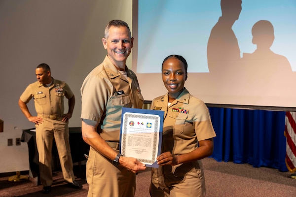 241010-JC800-1023 BETHESDA, Md. (Oct. 10, 2024) - Capt. William Deniston, lead inspector for the Medical Inspector General, awards a certificate of recognition to Lt. Nicolette Baker, manager of the command good order and discipline program,  during an out brief for MEDIG. (U.S. Navy Photo by Mass Communication Specialist 1st Class Heath Zeigler)