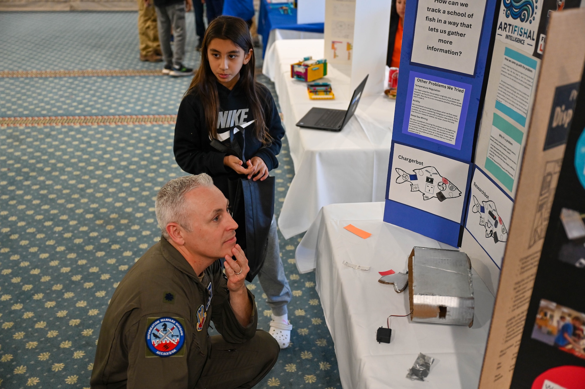 Lt. Col. Dana Lundy examines a student’s project during the Tidewater Chapter of the Armed Forces Communication and Electronics Association International STEM event at Joint Base Langley-Eustis, Virginia, Oct. 22, 2024. The event was attended by over 100 students, parents, JBLE personnel and industry professionals, and featured guest speakers and several engineering projects crafted by K-12 students from the local area.
