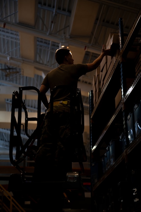 U.S. Air Force Senior Airman Cameron Ogden, 436th Operation Support Squadron Aircrew Flight Equipment technician, reaches for a box in the AFE warehouse at Dover Air Force Base, Delaware, Oct. 29, 2024. The AFE team provides inspections and maintenance for flight safety equipment such as parachutes, emergency escape slides and life rafts for the C-5M Super Galaxy and C-17 Globemaster III. (U.S. Air Force photo by Airman 1st Class Liberty Matthews)