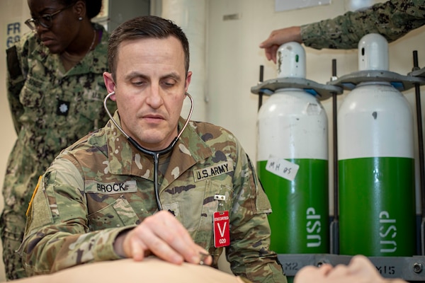 241017-N-KC192-1069 NORFOLK, Va. (Oct. 17, 2024) Lt. Col, Adam Brock, a periodontist assigned to Fort Gregg-Adams Dental Clinic Command, uses a stethoscope to examine a simulation manikin during dental officer triage training aboard the Wasp-class amphibious assault ship USS Iwo Jima (LHD 7), Oct. 17, 2024. Over the course of three days, Army and Navy dental officers from Iwo Jima, Navy Medicine Readiness and Training Command (NMRTC) Portsmouth and Fort Gregg-Adams Dental Clinic Command conducted mass casualty, tactical combat casualty care, and triage training. (U.S. Navy photo by Mass Communication Specialist 2nd Class Levi Decker)