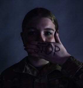 A women covers her mouth with stop written on it