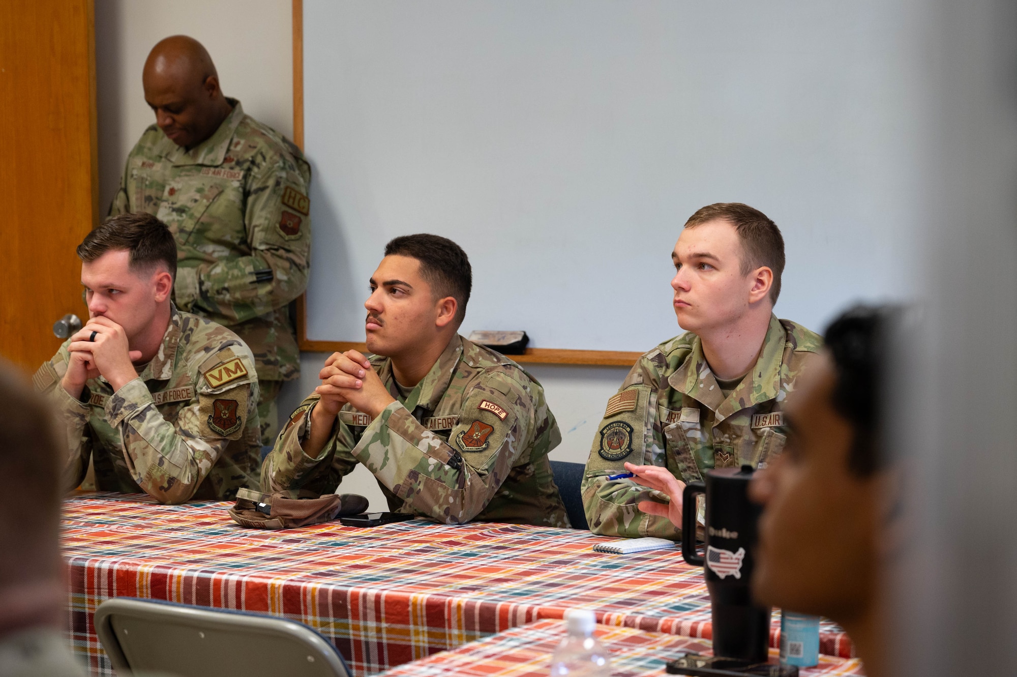 Airman 1st Class Ethan Roe, Airman 1st Class Luis Medina III and Airman 1st Class Alex Artho listen to a speech given by HOPE leadership.