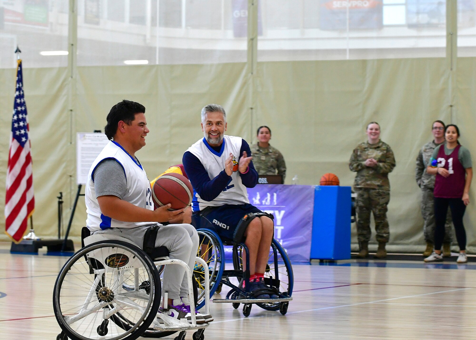 Two players in wheelchairs with one holding a basketball.