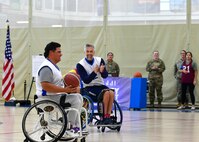Two players in wheelchairs with one holding a basketball.