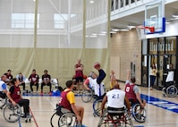 Players in wheelchairs gather around a hoop in during a wheelchair basketball game.