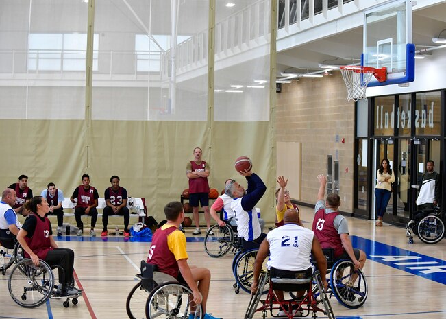 Players in wheelchairs gather around a hoop in during a wheelchair basketball game.